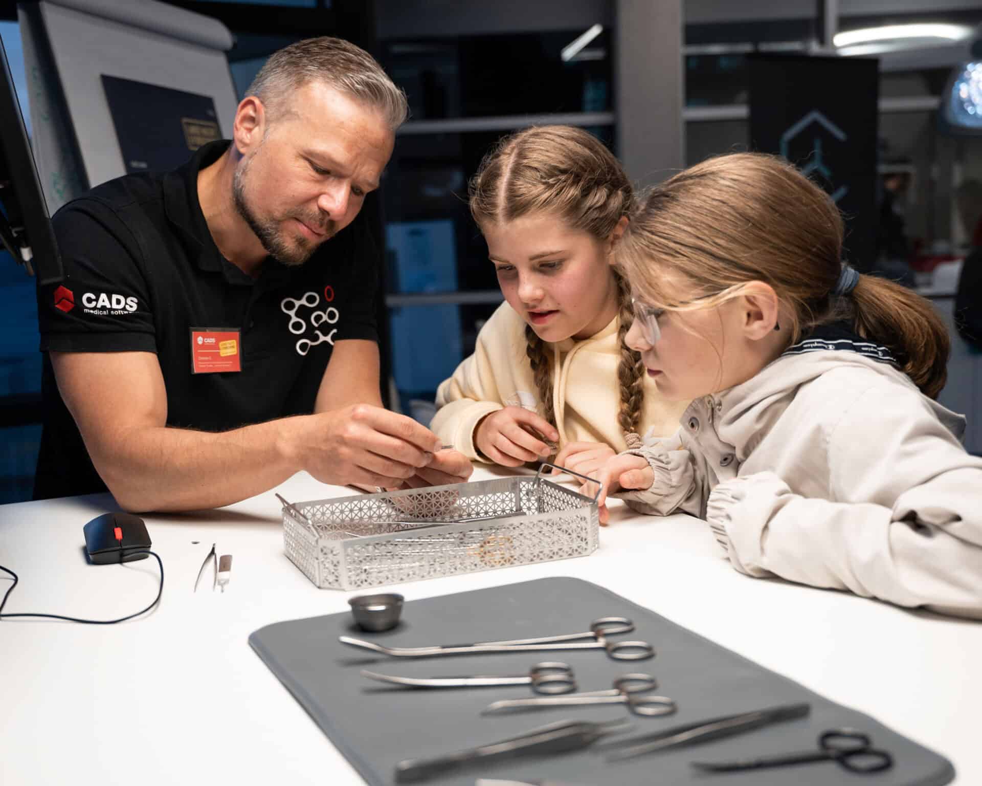 Mitarbeiter erklärt Kindern innovative Hightech-Tools bei der langen Nacht der Forschung bei CADS.