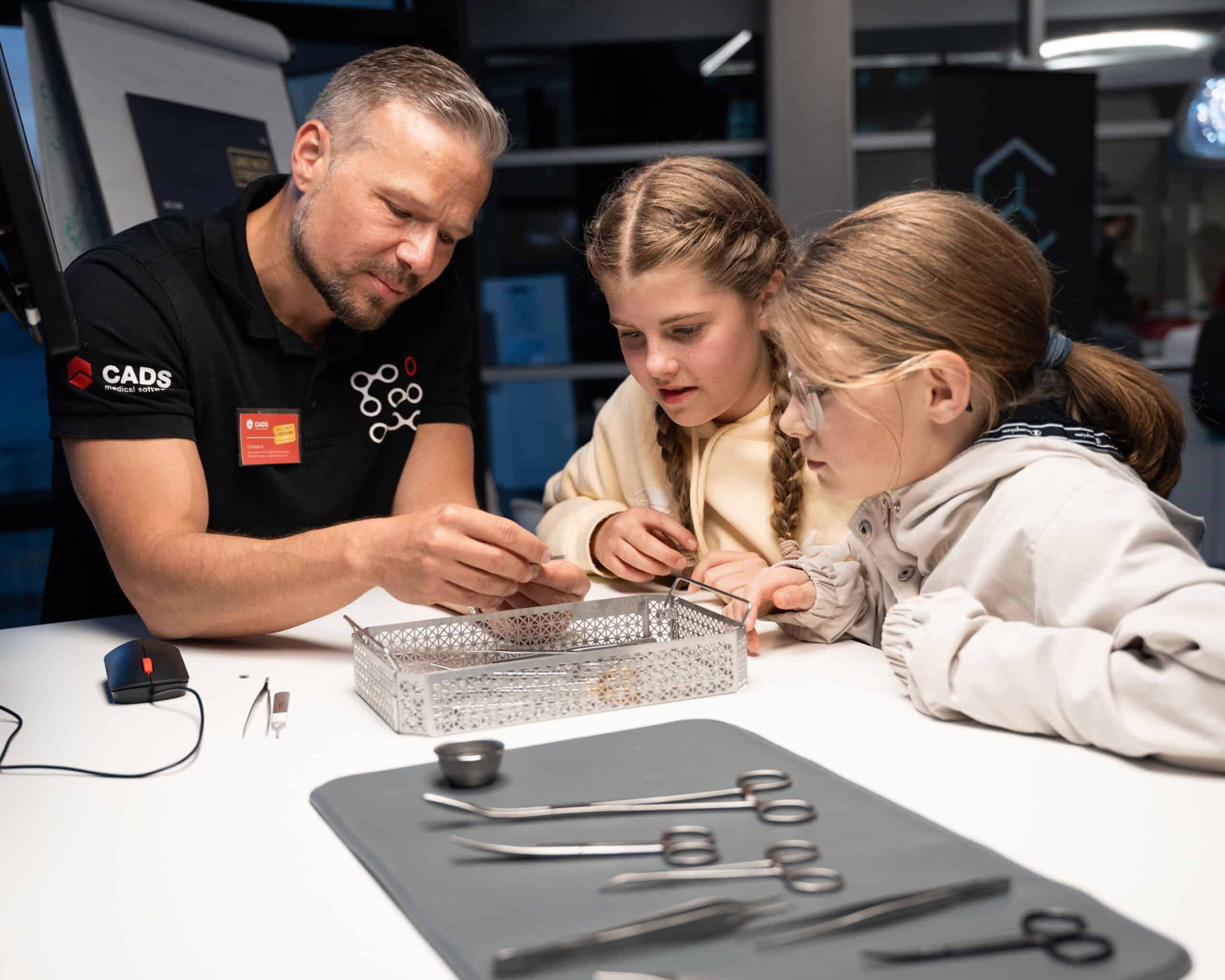 Mitarbeiter erklärt Kindern innovative Hightech-Tools bei der langen Nacht der Forschung bei CADS.